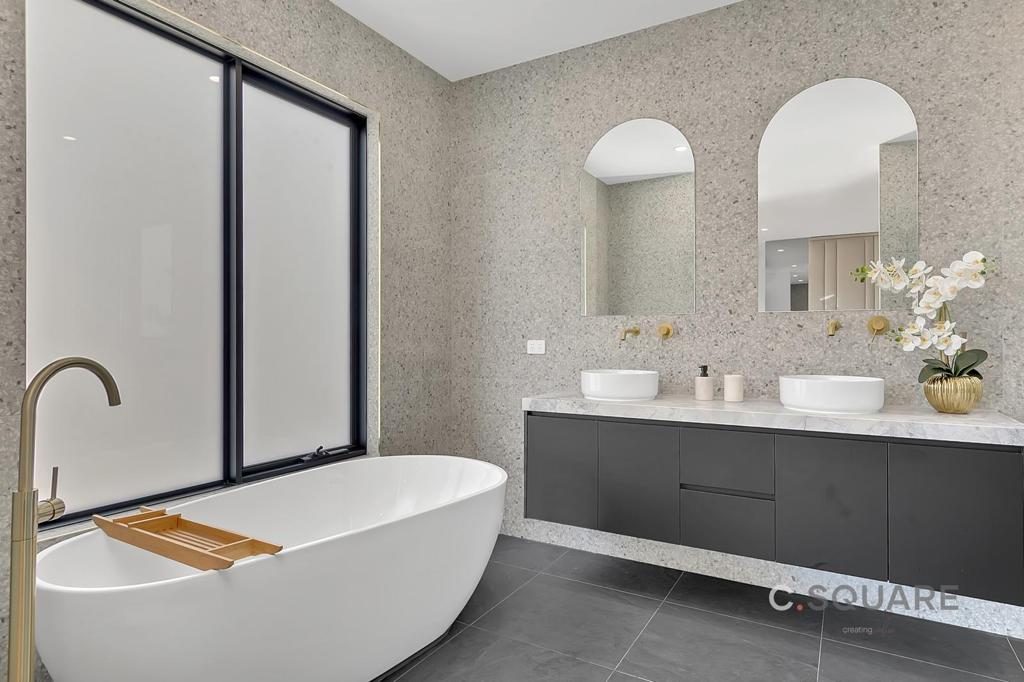 Freestanding bath and double vanity under arched mirrors with a black-framed window