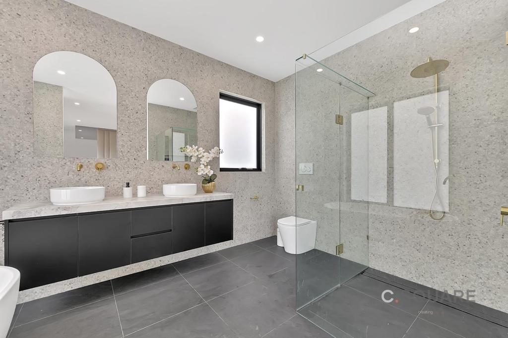 Large bathroom with double floating vanity, arched mirrors and a frameless glass shower