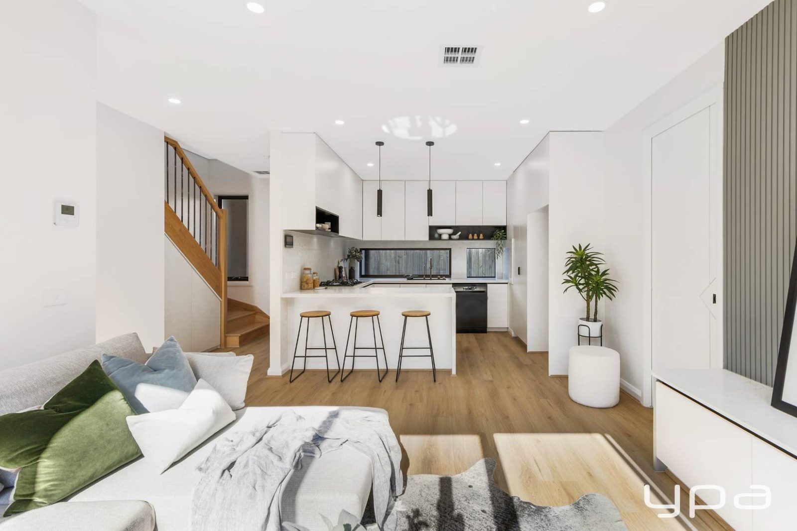 Open-plan kitchen and living area with timber staircase and black pendants